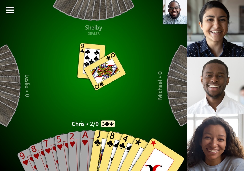 Screenshot of a game of Bid Whist with video chat enabled in Trickster Cards. Three videos for the other players are displayed to the right and a video preview for the local player is displayed near the top-right.